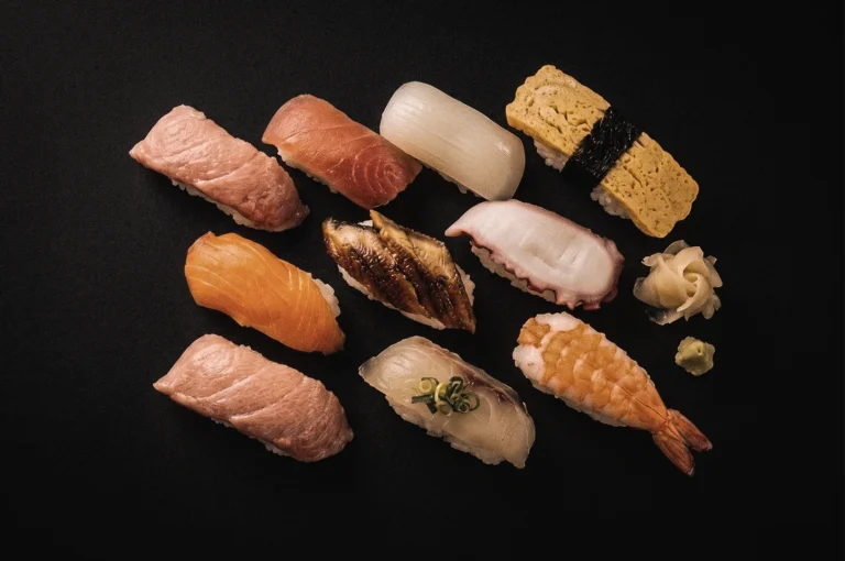 Overhead flat lay of assorted Edomae nigiri sushi including tuna, salmon, squid, eel, shrimp, octopus and tamago, showcasing traditional Edo-style sushi toppings and seasonal seafood.