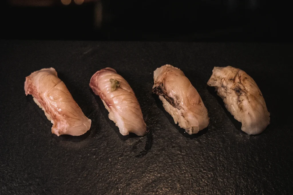 Close-up eye-level shot of assorted nigiri sushi featuring premium seafood toppings over hand-pressed shari rice, showcasing traditional Japanese nigiri sushi craftsmanship and omakase dining experience.