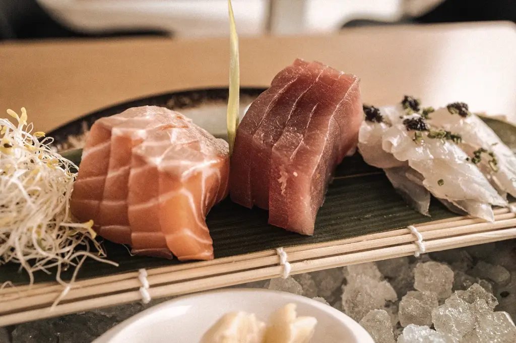 Eye-level close-up of premium salmon, tuna, and white fish sashimi served over ice with shredded daikon garnish, highlighting fresh seafood quality and traditional Japanese sashimi presentation.