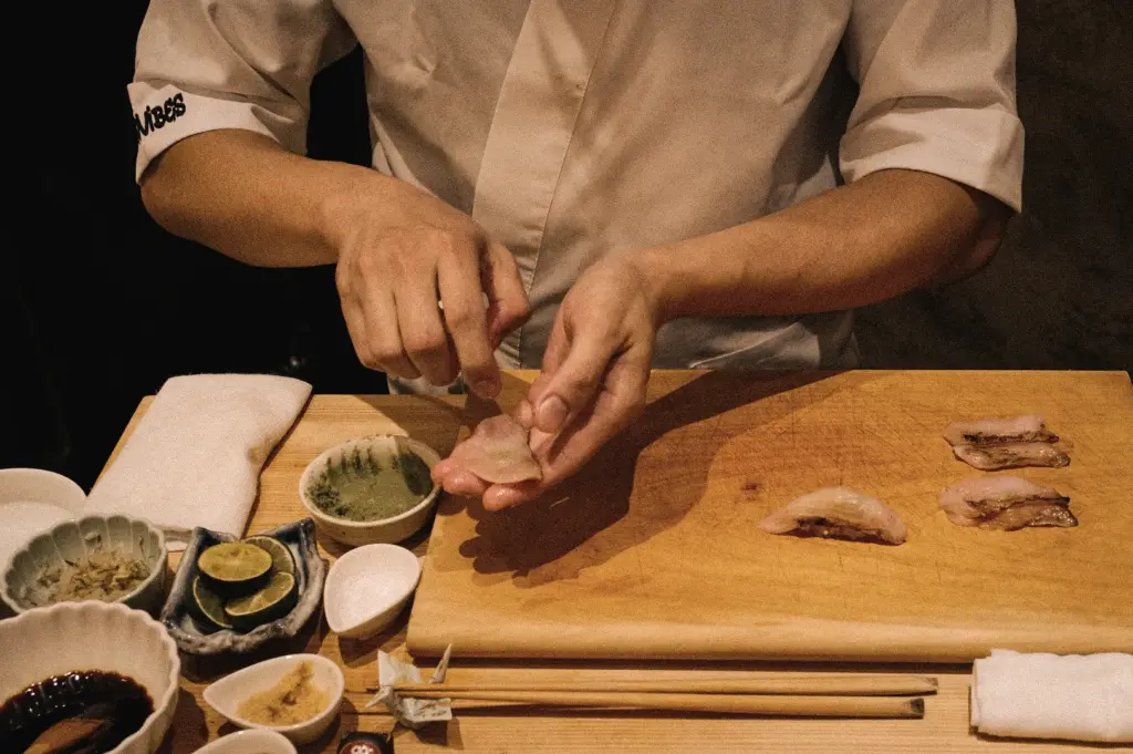 High-angle close-up of a sushi chef handcrafting nigiri at Sushi To Sumi Singapore, demonstrating traditional Japanese sushi preparation techniques and omakase-quality craftsmanship.