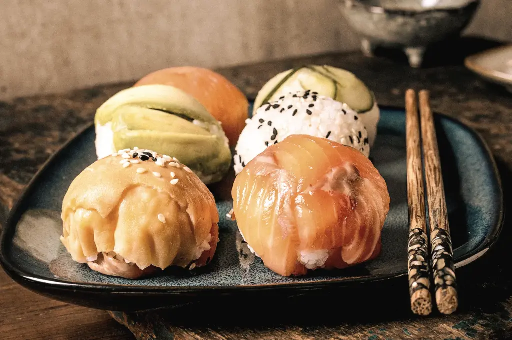Eye-level close-up of assorted temari sushi topped with salmon, avocado, cucumber, sesame seeds, and seafood on a black plate with chopsticks, showcasing colorful Japanese ball-shaped sushi.