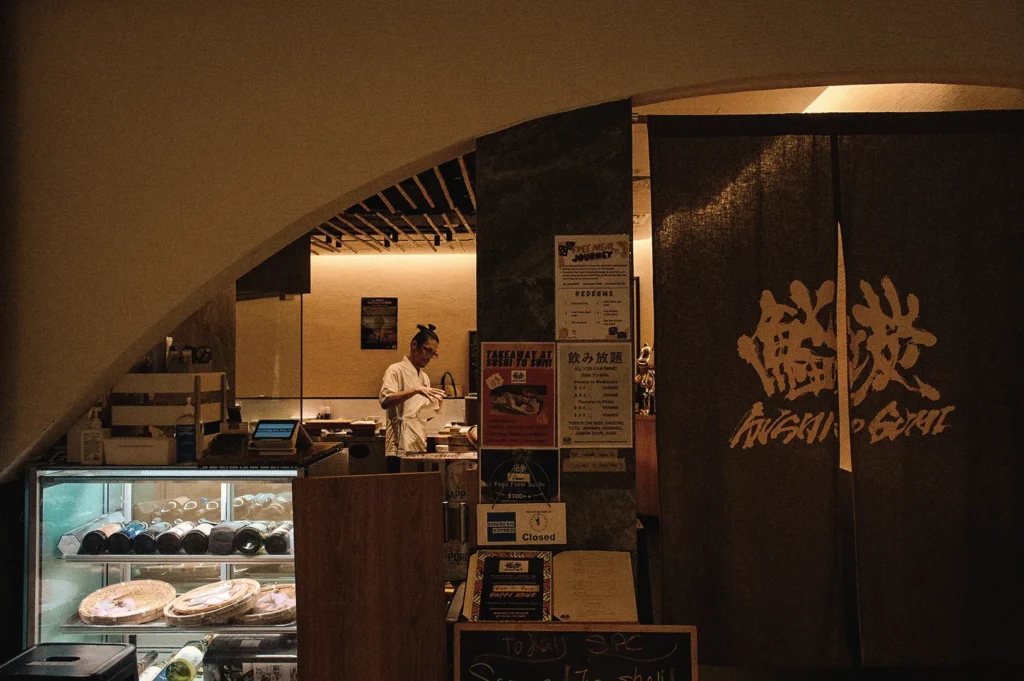 Wide-angle eye-level view of Sushi to Sumi in Singapore, a Japanese standing sushi bar featuring an open kitchen, fresh seafood display, and traditional noren entrance, reflecting authentic Edomae-inspired sushi dining.