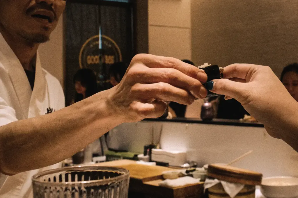 Eye-level close-up of a chef serving freshly prepared nigiri sushi directly to a guest at Sushi To Sumi Singapore, showcasing an authentic omakase dining experience and traditional Japanese sushi craftsmanship.
