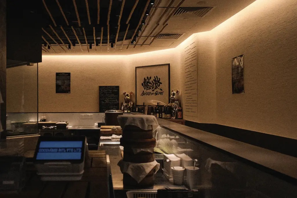 Wide-angle interior view of a Japanese sushi restaurant featuring a traditional sushi counter, warm ambient lighting, and an intimate omakase dining atmosphere in Singapore.